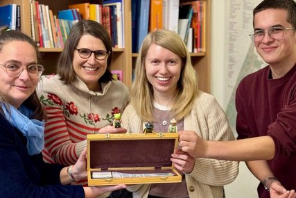 Vier Personen halten einen geöffneten Schachkoffer in den Händen. - Copyright: Katharina Schneider