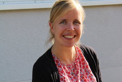 Eine Frau mit mittelangen blondem Haaren sind zu einem Zopf zusammengebunden. Sie trägt ein Bluse mit dunkler Jacke darüber und lächelt in die Kamera - Copyright: Franziska Nagel