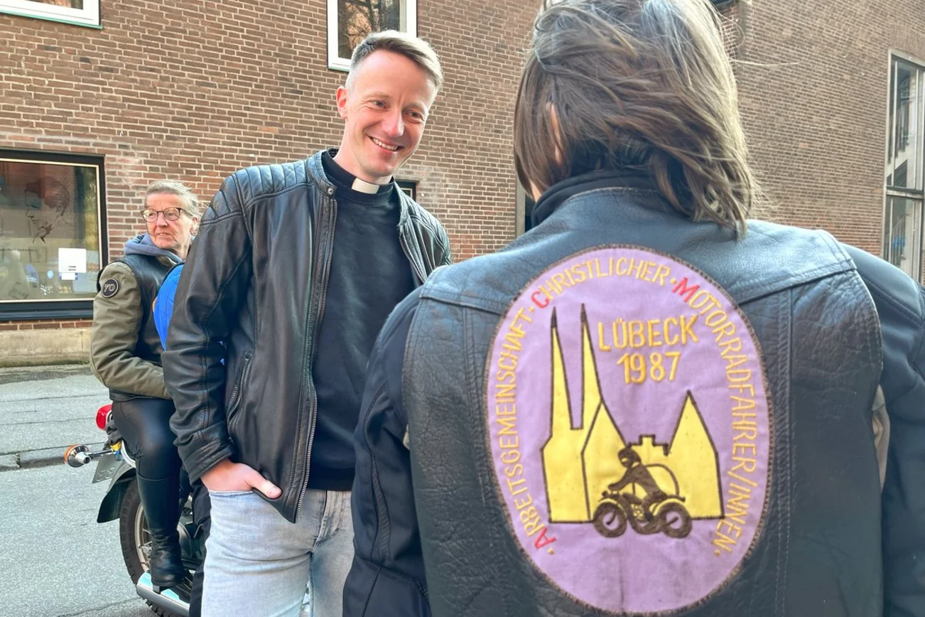 Ein Mann spricht mit einer Bikerin. 