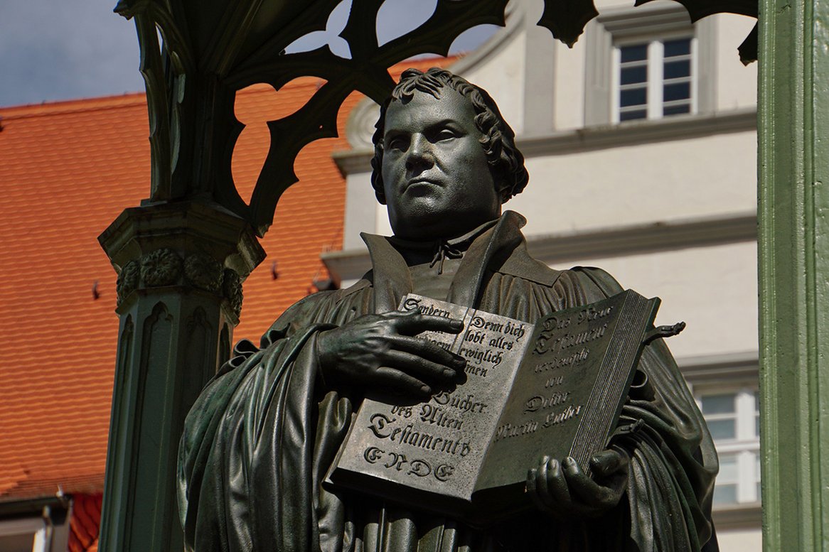 Eine Statur von Martin Luther, er hält ein Buch, auf der linken Seite steht etwas vom alten Testament, auf der rechten Seite vom neuen Testament.