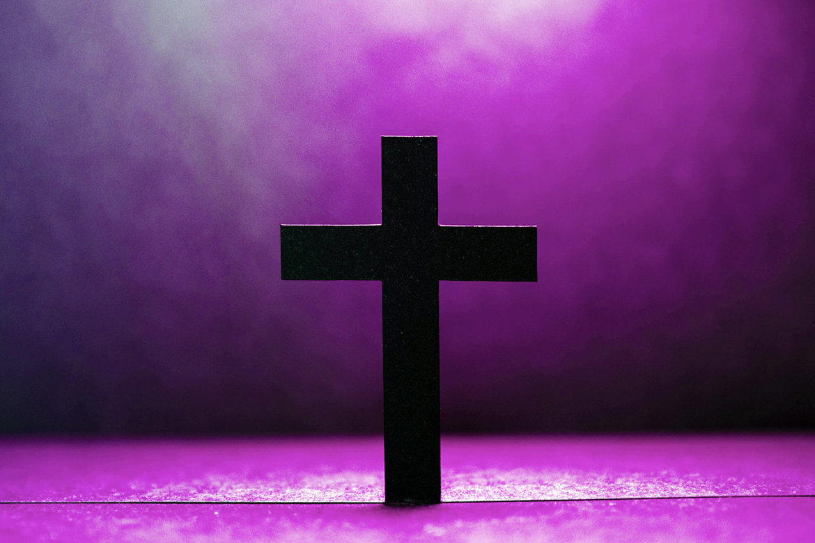 Ein dunkles Kreuz vor lila Hintergrund