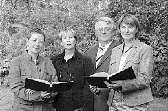 Vier Personen, drei Frauen, ein Mann stehen nebeneinander, links und rechts halten die Damen jeweils eine offene schwarze Mappe in den Händen