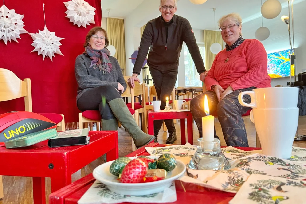 Drei Personen sitzen in harmonischer Runde in einem Raum. 