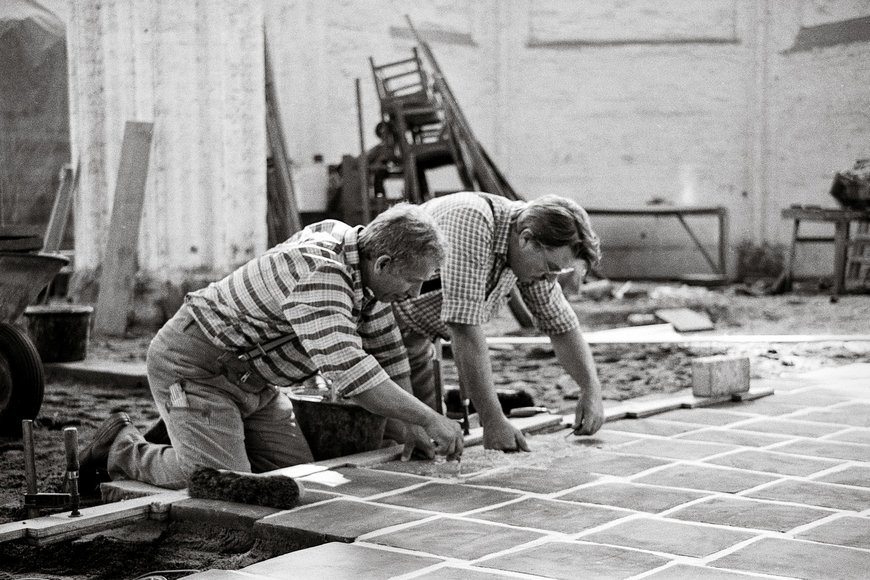 Historisches Schwarz-Weiß-Foto zeigt zwei Männer, die auf dem Boden einer Kirche knien und Steine verlegen. - Copyright: Lübecker Nachrichten / Alice Kranz-Pätow