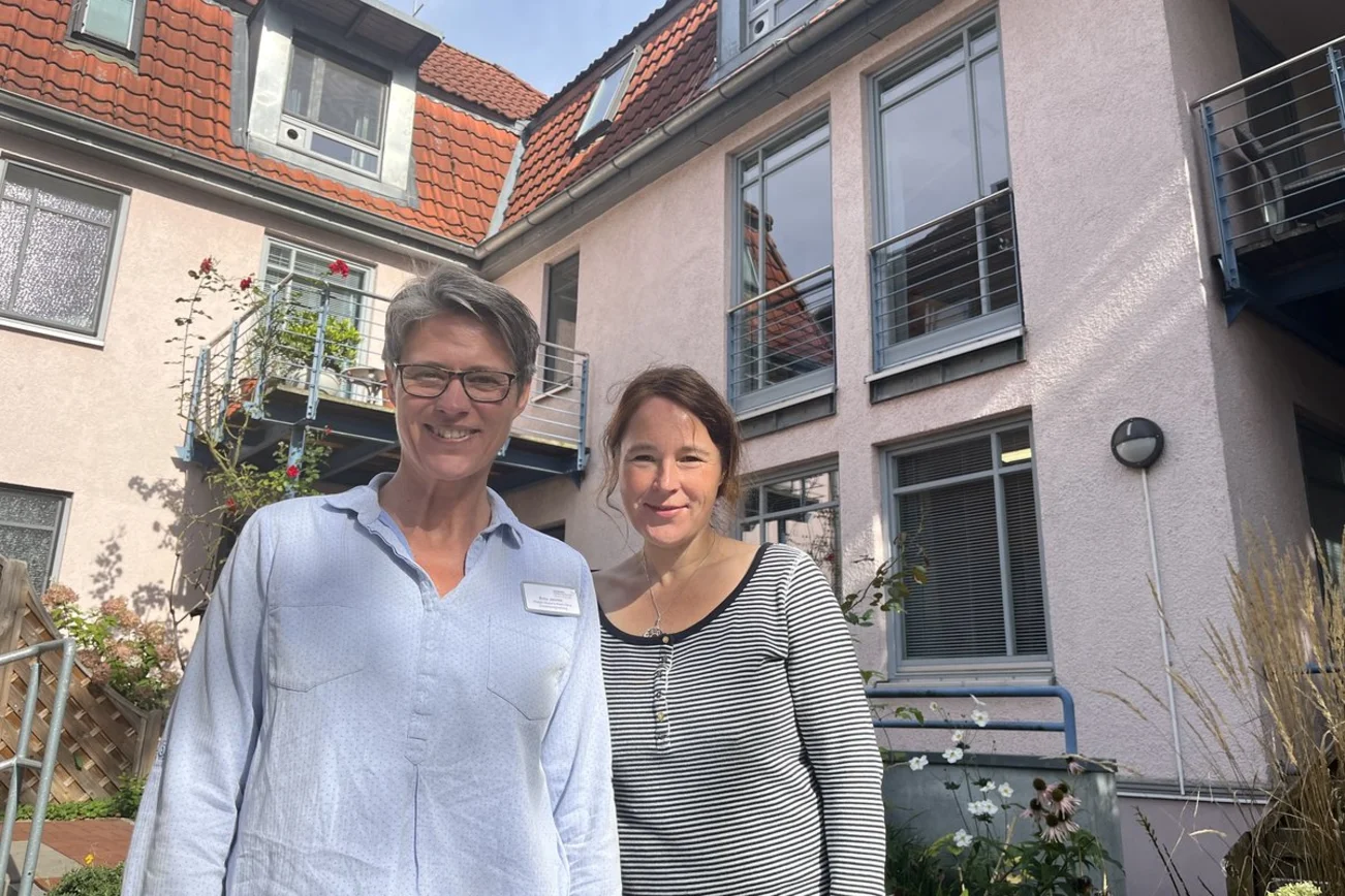 Zwei Frauen stehen vor einem Haus in der Sonne