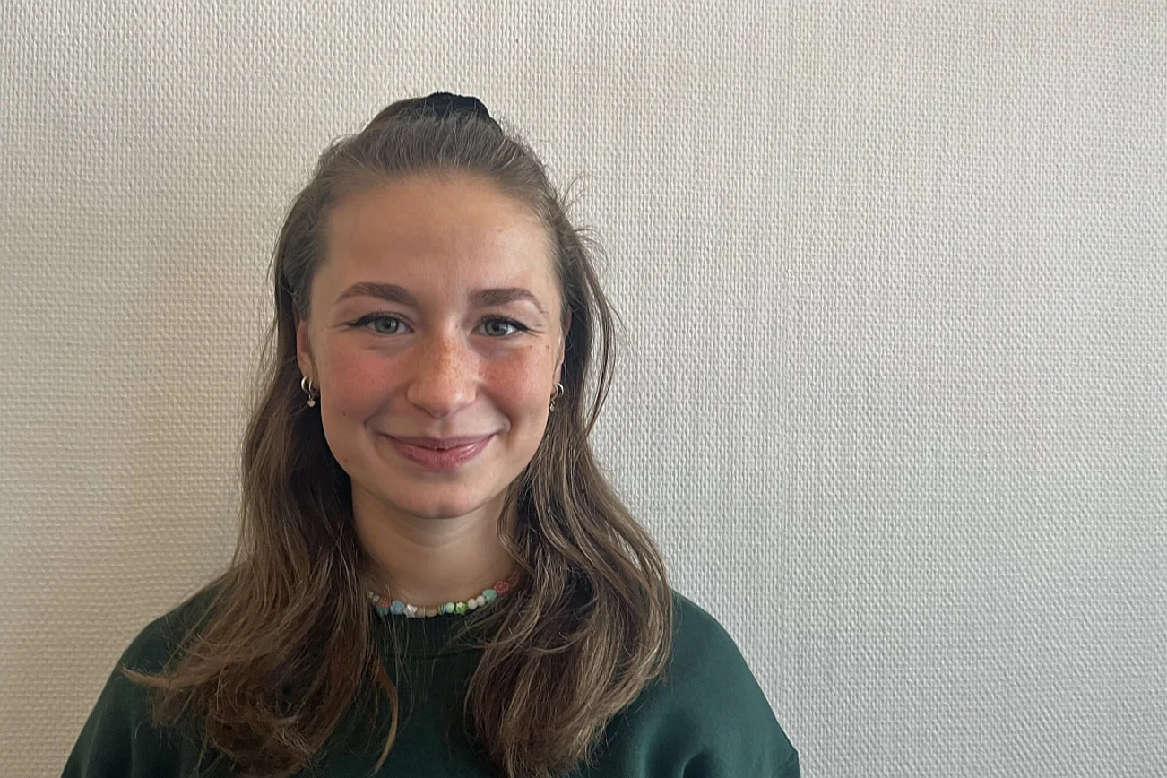 Eine junge Frau mit langen Haaren lächelt in die Kamera