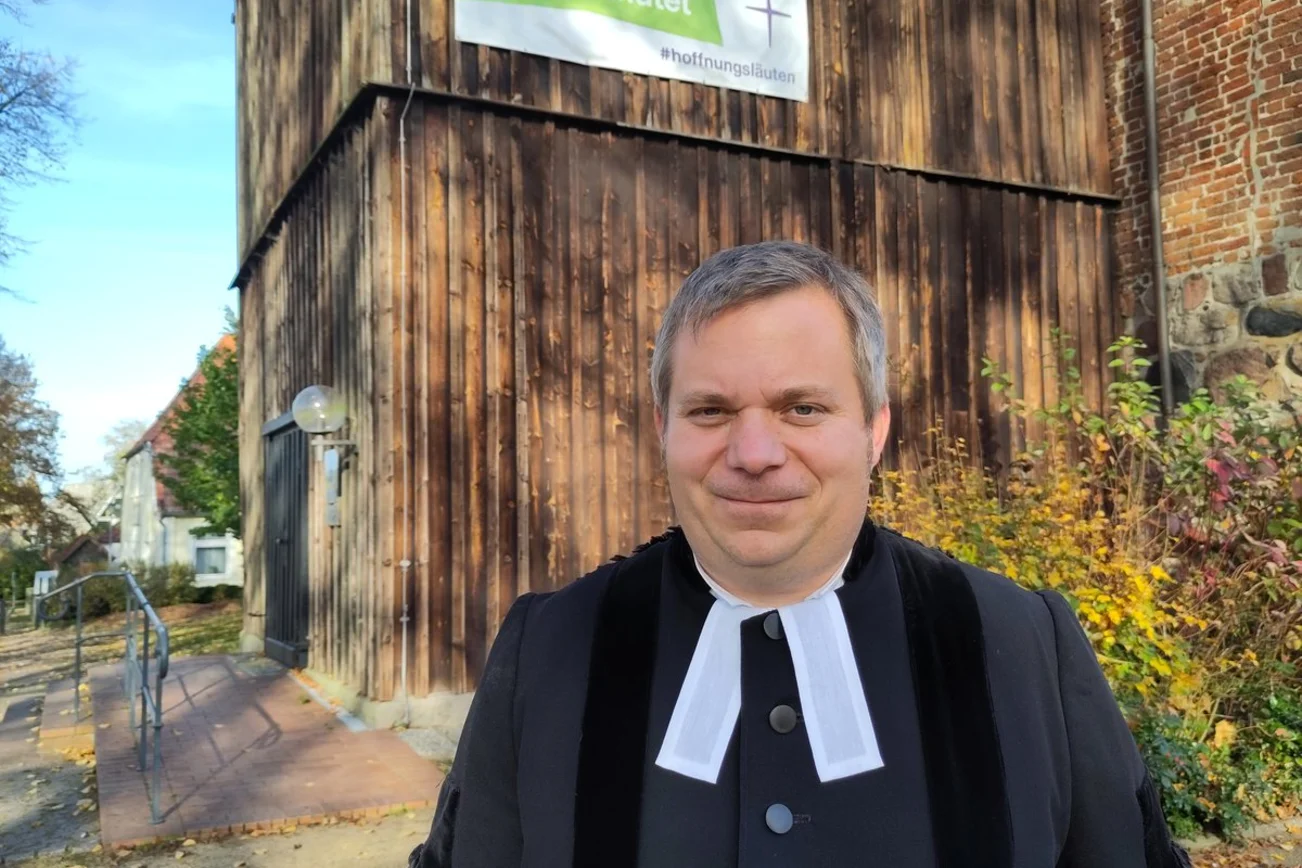 Ein Pastor steht vor einer Kirche