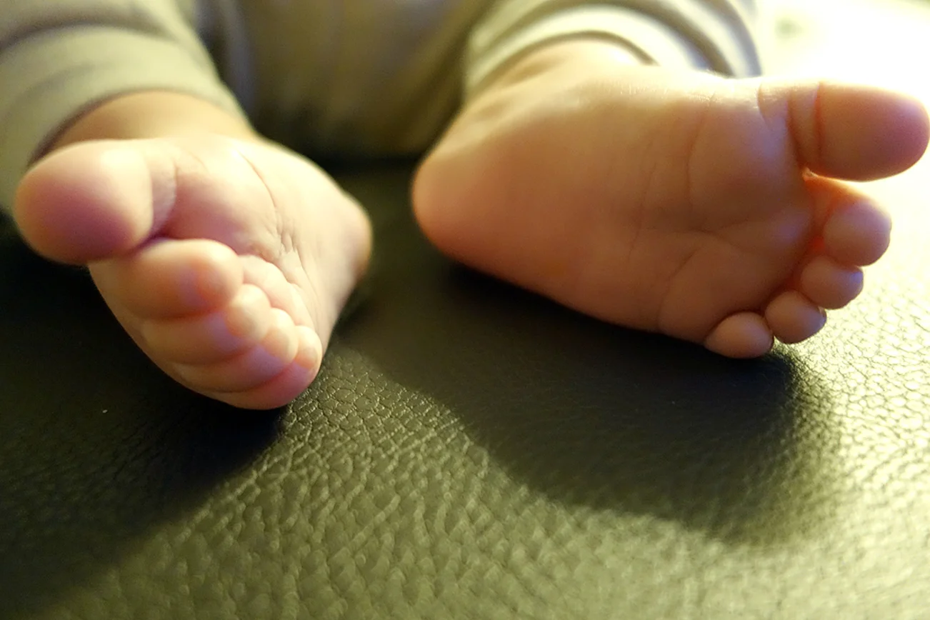 Kleine Babyfüße auf einer Couch.