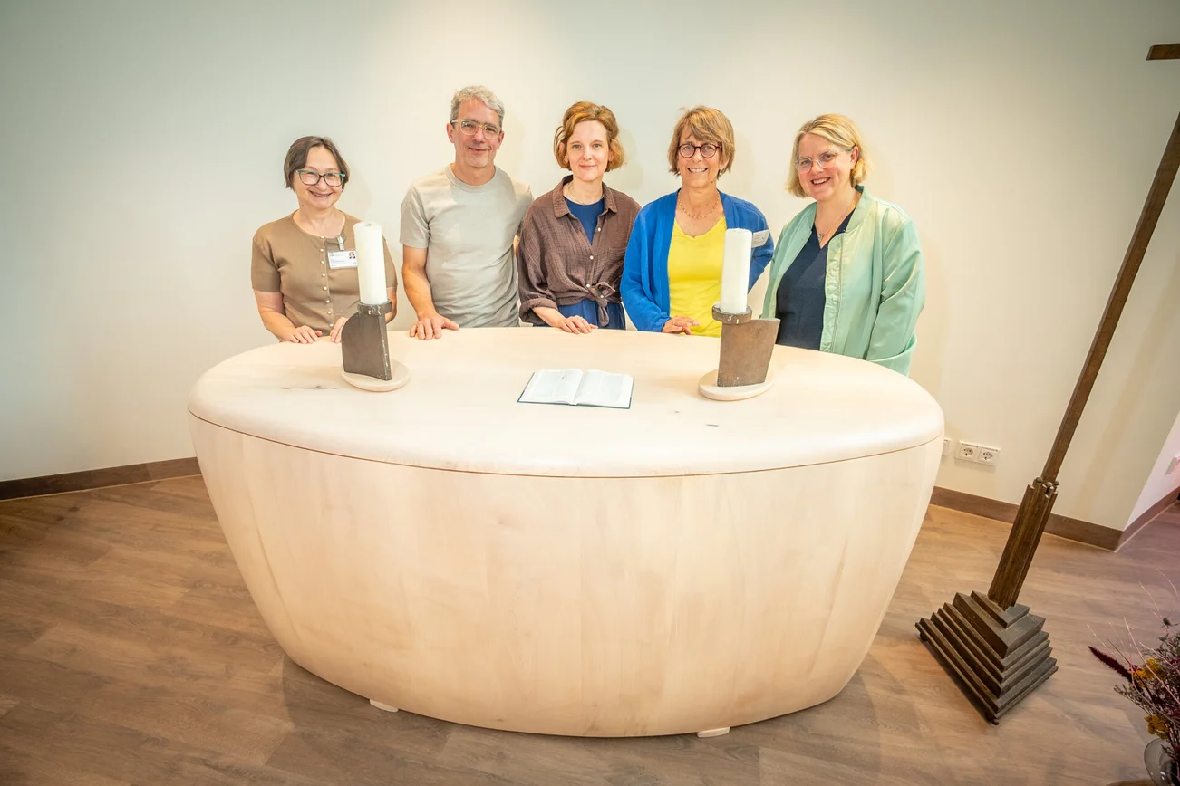 Gruppe an Menschen steht hinter dem neuen Altar im Raum der Stille