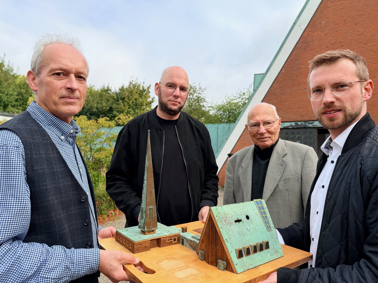 Vier Männer mit einem Kirchenmodell