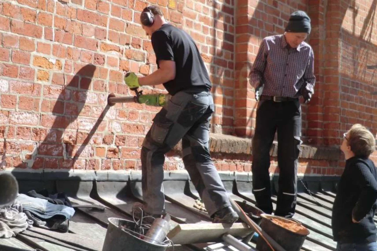 Männer bohren im Mauerwerk des Dom zu Lübeck.