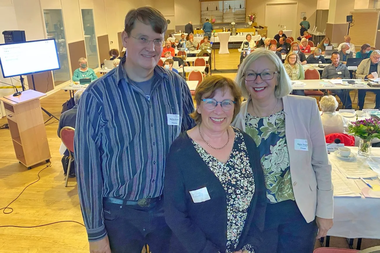 Drei Personen schauen in die Kamera. 