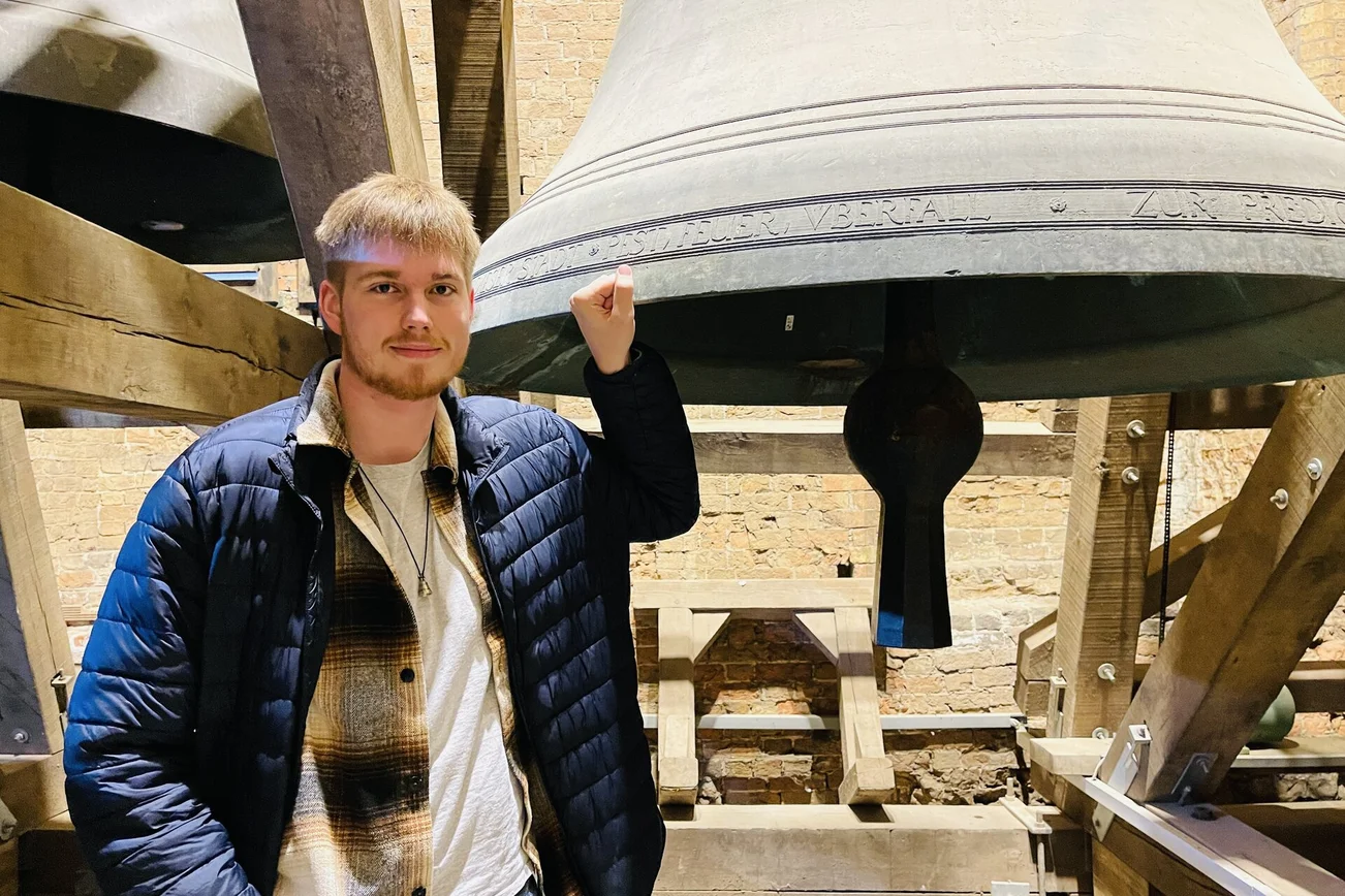 Ein junger Mann steht vor der großen Glocke der Marienkirche.