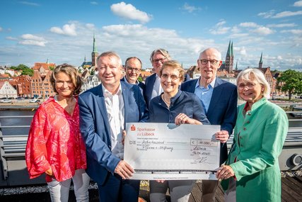 Sieben Menschen lächeln mit einem Scheck in der Hand. - Copyright: Lena Modrow