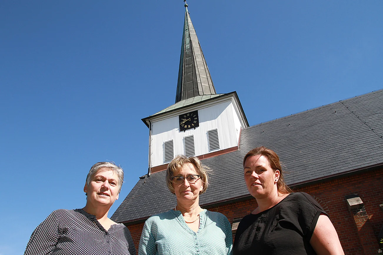V. li.: Pastorin Wiebke Rogall-Machona, Ingrid Neervoort  und Sandra Havemann vor dem frisch gestrichenen Kirchturm inklusive Kirchturmuhr. 
