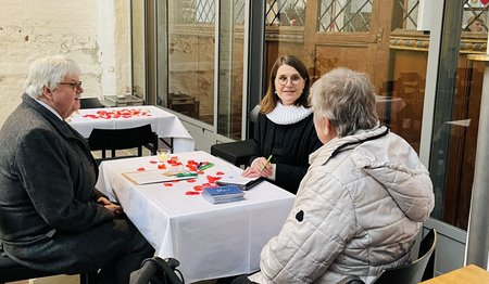 Eine Pastorin spricht mit einem älteren Paar.