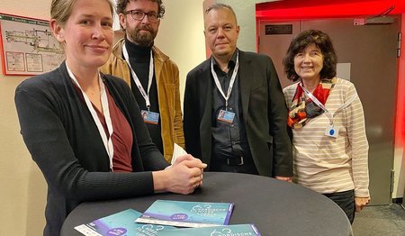 Gruppenbild, vier Personen lächeln in die Kamera.