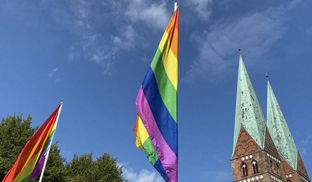 Eine Regenbogenflagge und ein Kirchturm