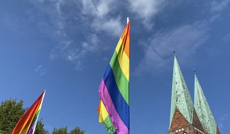 Eine Regenbogenflagge und ein Kirchturm