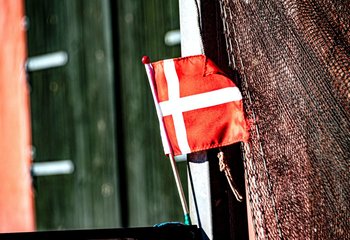 Eine dänische Flagge weht an einem Fischerboot.  - Copyright: Palle Knudson / Unsplash