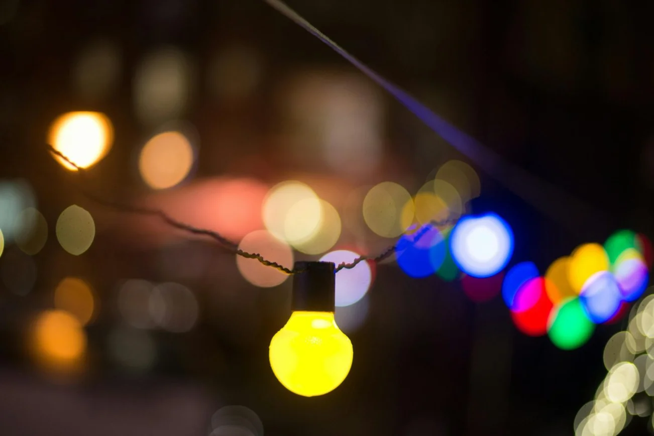 Bunte Glühbirnen an einer Lichterkette leuchten im Dunkeln.