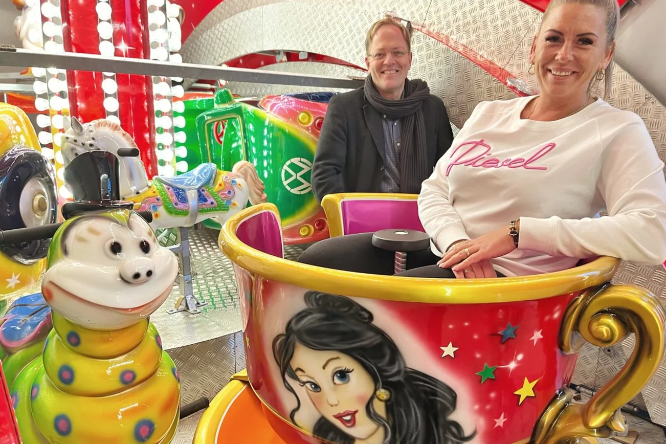 Zwei Personen sitzen in einem Kinderkarrussel