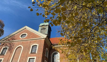 Kirche vor blauem Himmel und herbstlichem Laub. 