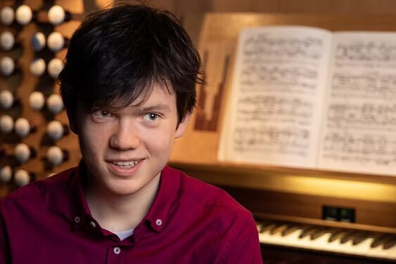 Der junge Organist Julian Emanuel Becker vor dem Spieltisch einer Orgel - Copyright: Philippe Stier