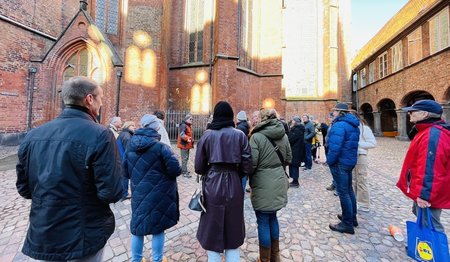Eine Gruppe Menschen steht vor der St.-Marien-Kirche bei schönem Wetter