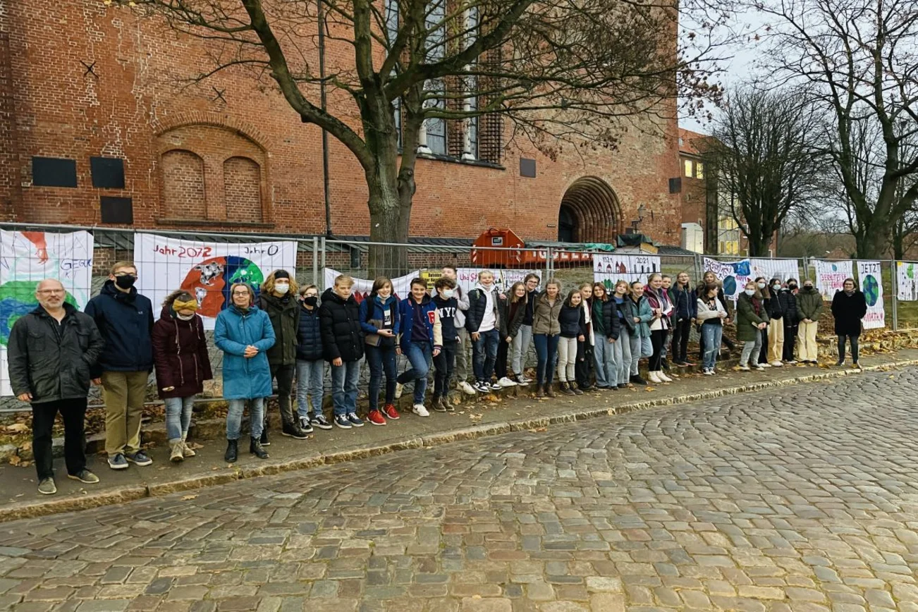 Menschen vor einem Bauzaun mit Bannern.