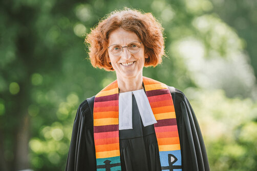 Eine Frau im Talar lächelt in die Kamera.