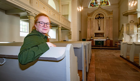 Eine Frau sitzt in einer Kirche.