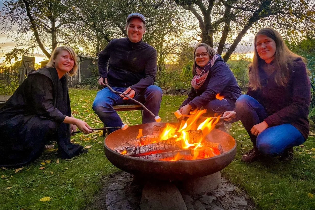 Gruppe von menschen steht um eine Feuertonne herum. 