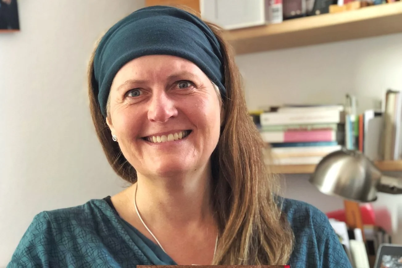 Eine Frau sitzt lächelnd in ihrem Büro. 