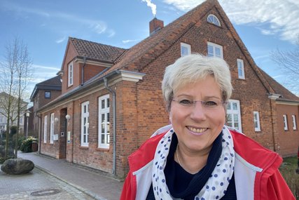 Eine Frau steht lächelnd vor einem Haus.  - Copyright: Bastian Modrow