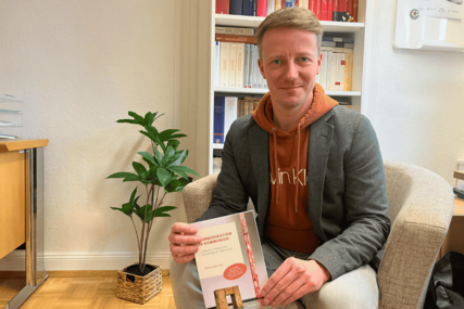 Pastor Knöller sitzt auf einem Sofa mit einem Buch in der Hand - Copyright: Mathias Stanierowski