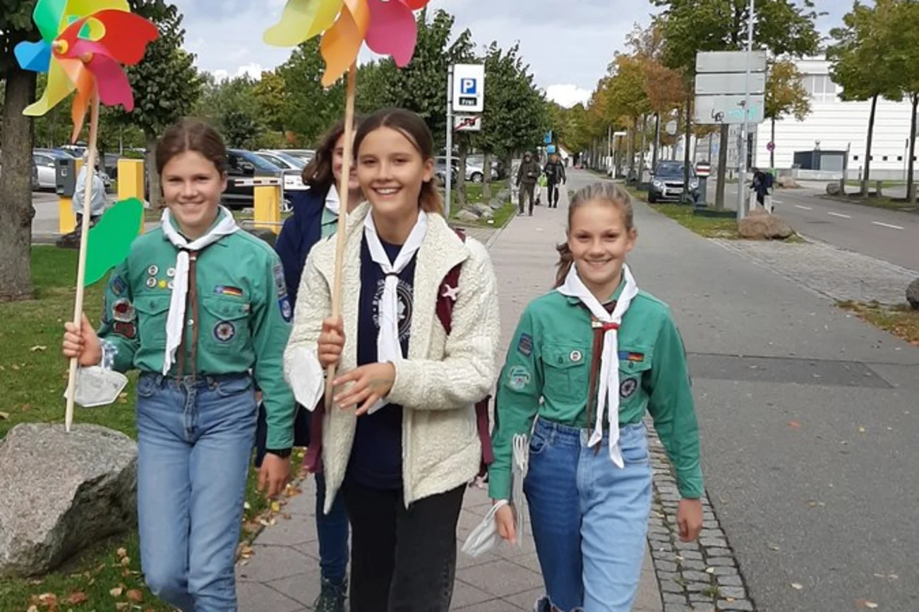 Drei Pfadfinder mit bunten Windmühlen