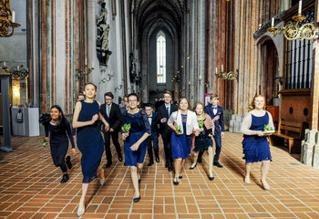 Junge Menschen laufen fröhlich in festlicher Kleidung durch eine Kirche. - Copyright: Thorsten Wulff