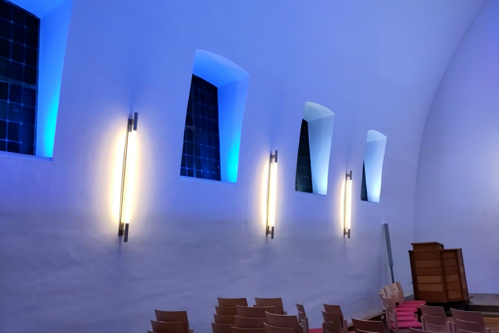Moderne Lampen an der einer blau erleuchteten Kirchenwand.