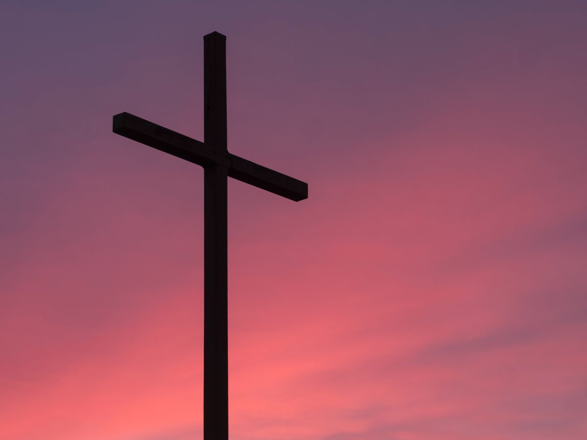 Ein Kreuz vor rötlichem Himmel