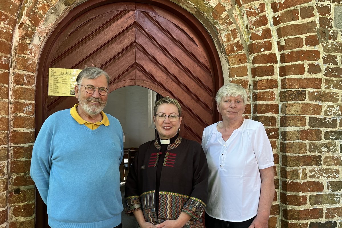 Drei Personen vor dem Eingang einer Kapelle.