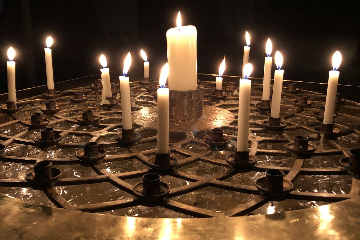 Eine große und mehrere kleine Kerzen leuchten auf einem breiten Kerzenleuchter.