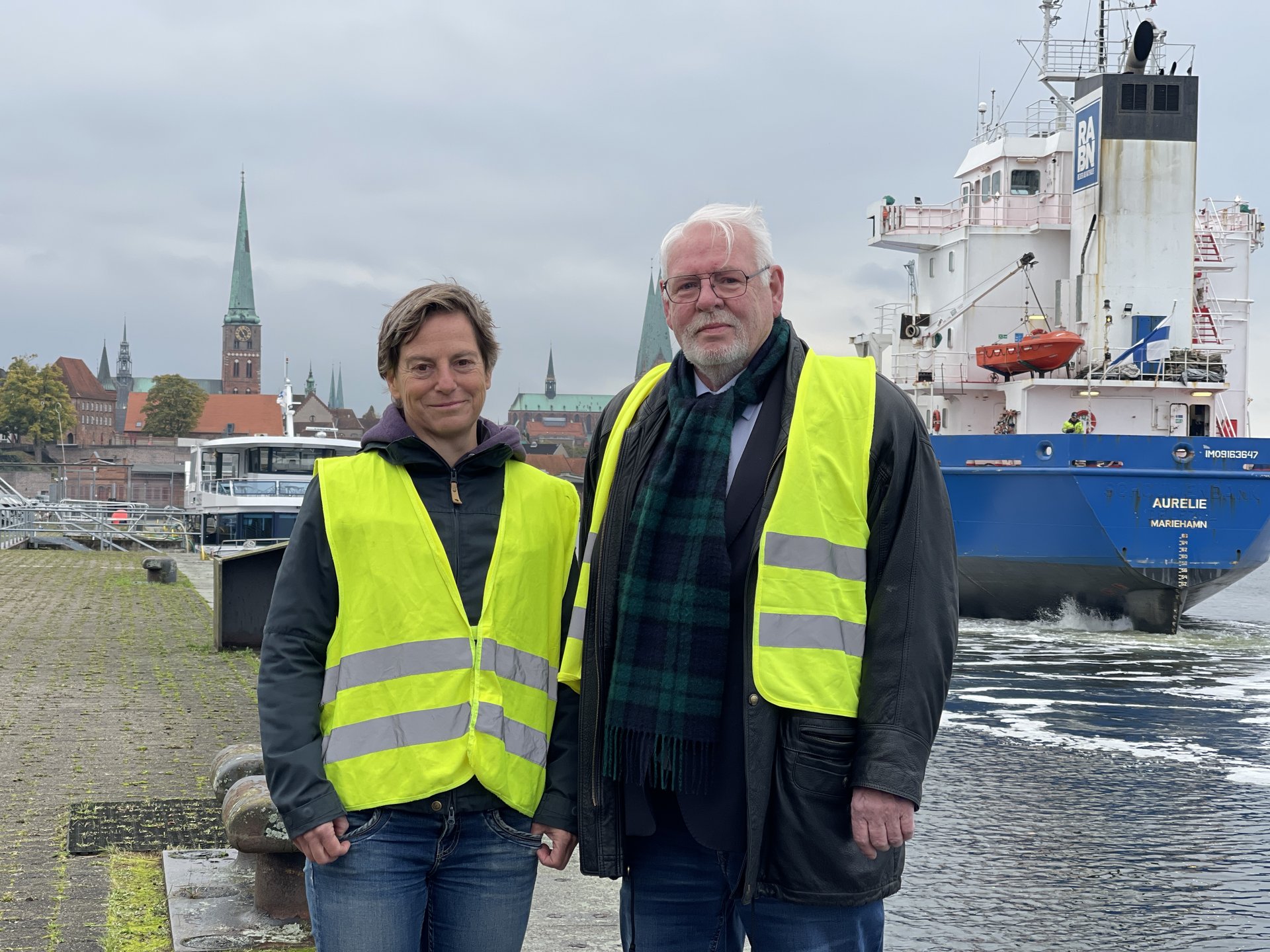 Zwei Menschen vor einem Schiff. 