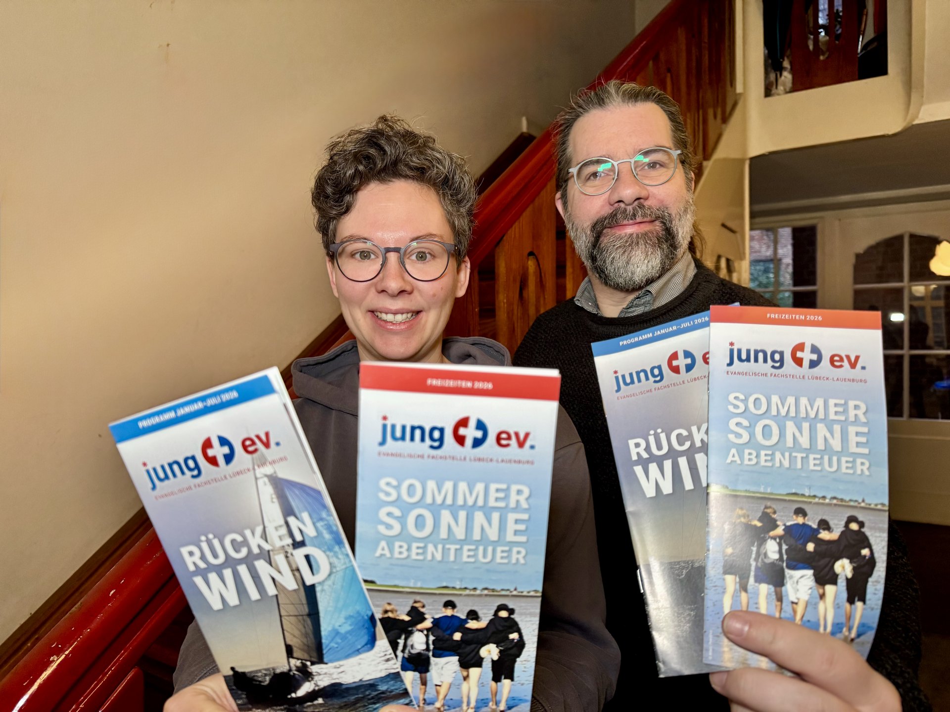 Zwei Personen halten Flyer in die Kamera