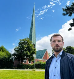 Mann steht vor einer Kirche