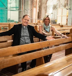 Ein Mann und eine Frau sitzen auf Kirchenbänken