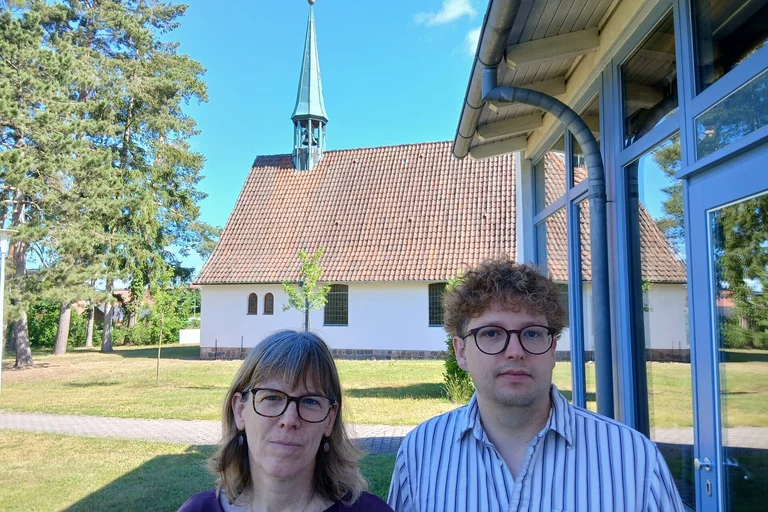 Eine Frau und ein Mann stehen vor einer Kirche.