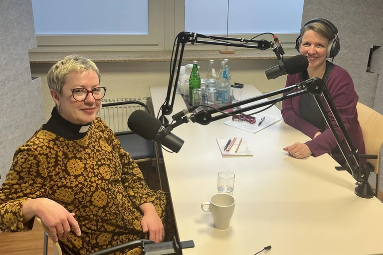 Zwei Frauen sitzen in einem Aufnahmestudio an Mikrofonen