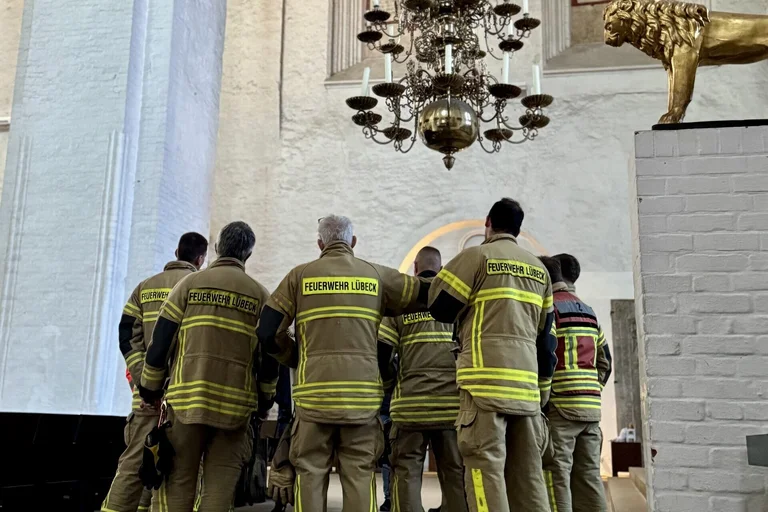 Feuerwehr Leute stehen unter einem alten Leuchter in einer Kirche.