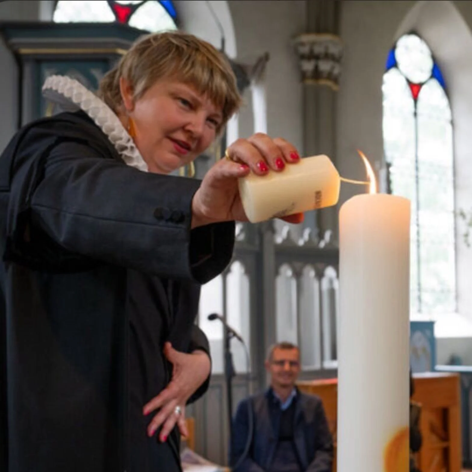 Pastorin zündet Kerze an